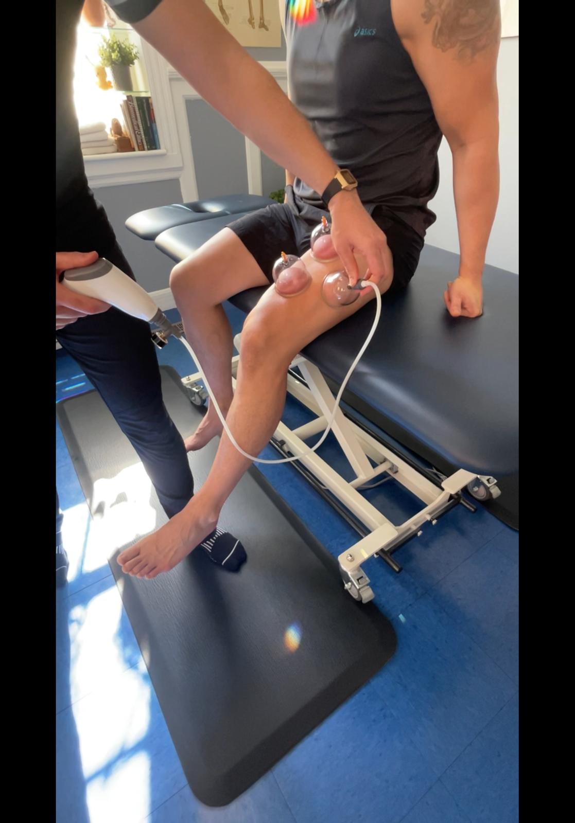 Physical therapist performing leg and knee assessment on a client lying on a treatment table