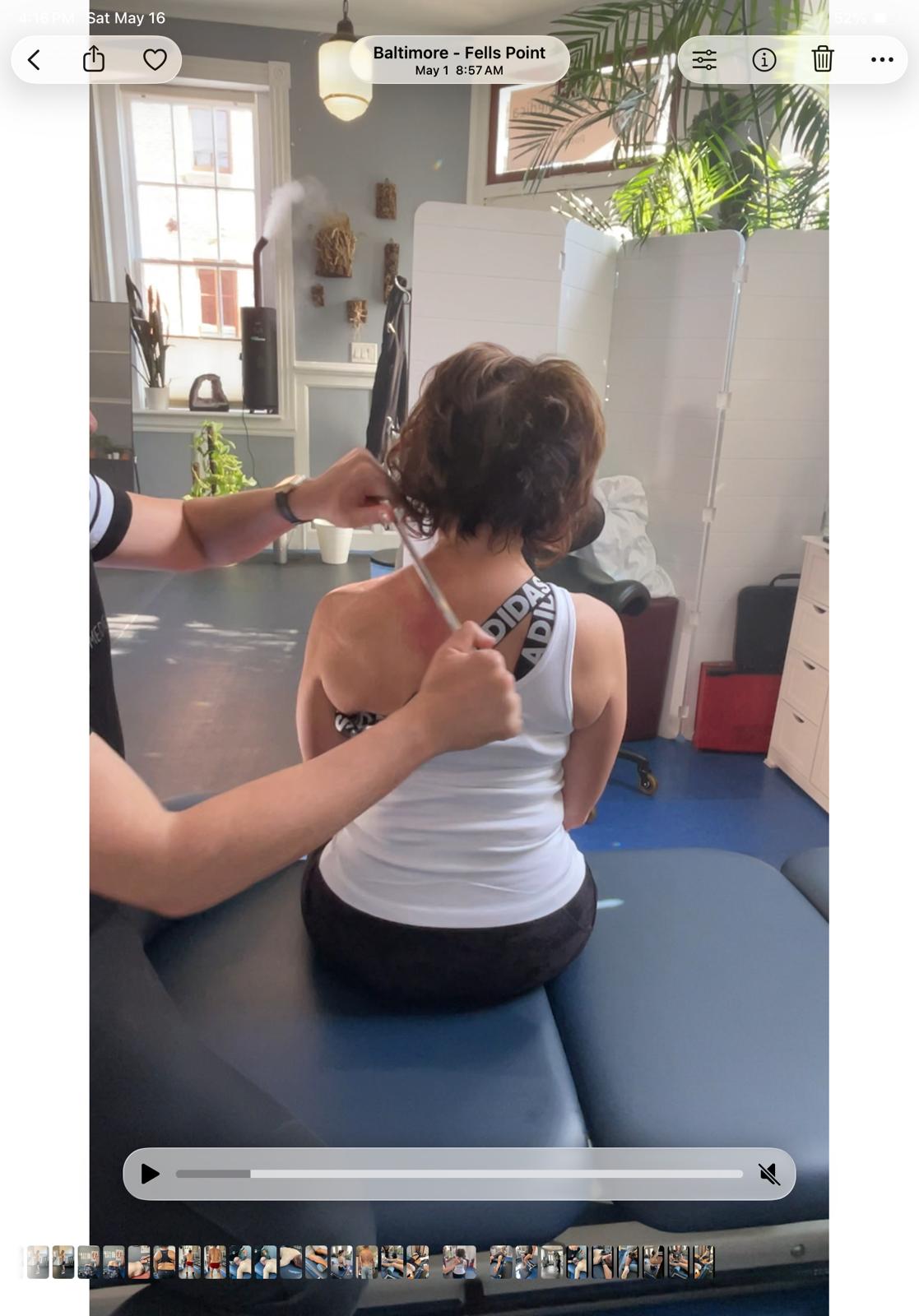 Therapist performing shoulder and neck assessment on a client seated on a treatment table