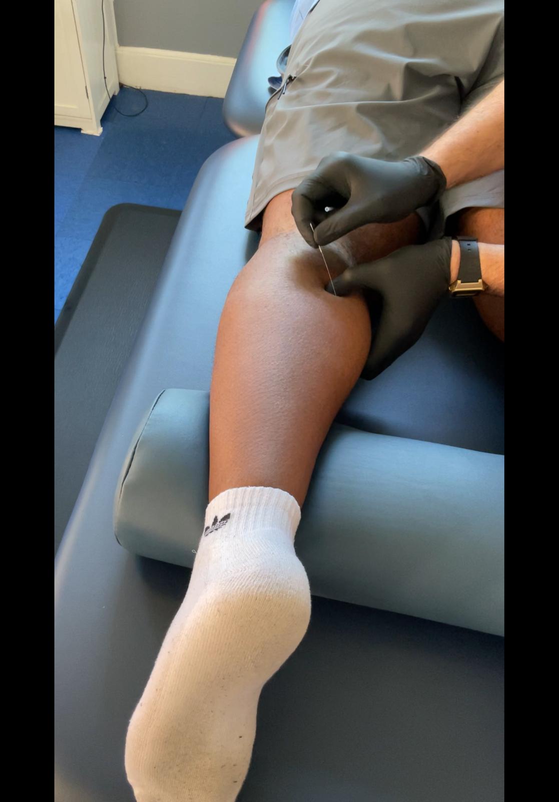 Physical therapist performing soft tissue mobilization on a client's leg using hands-on technique