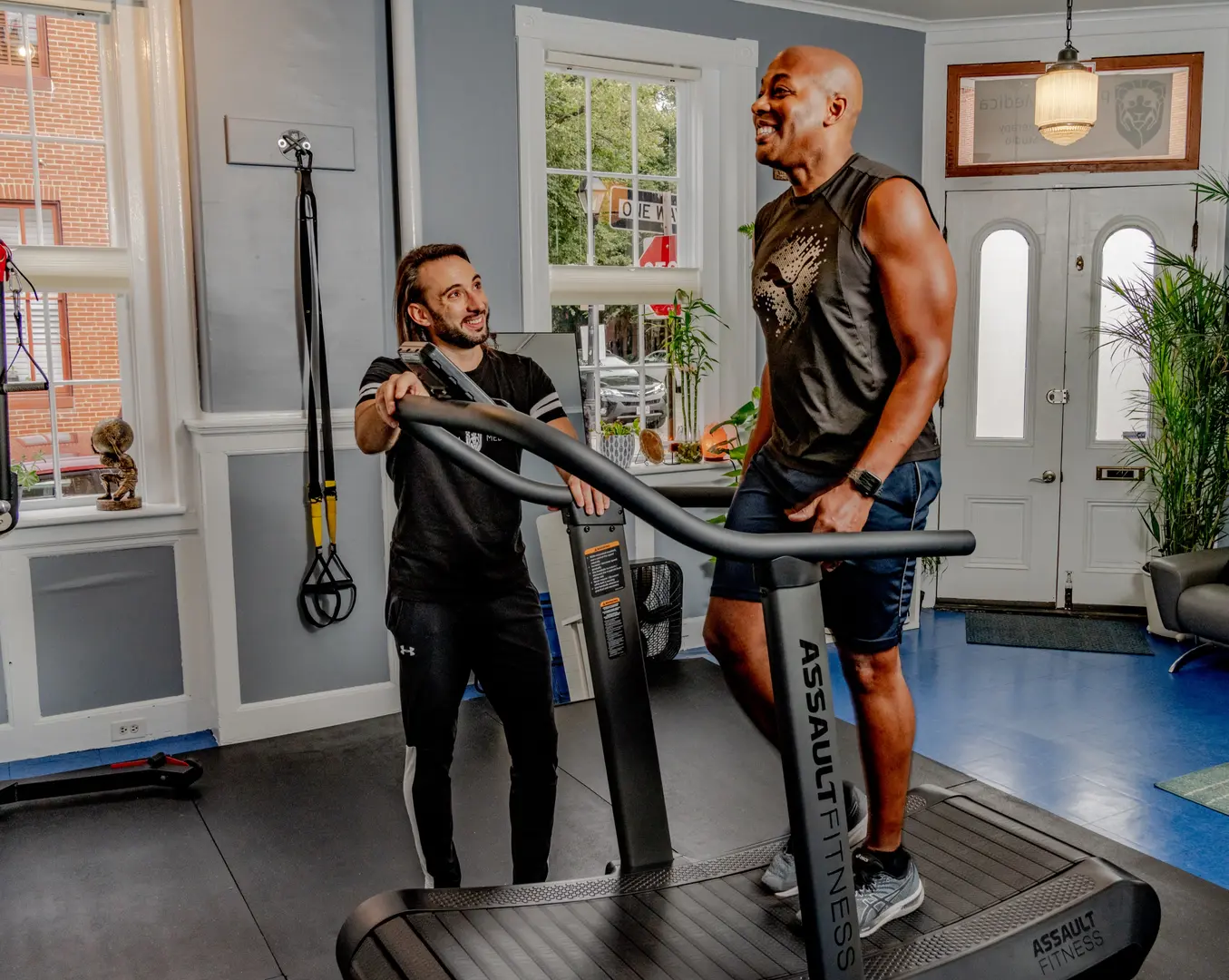 Practitioner instructing client on functional patterns training using suspension equipment in clinic